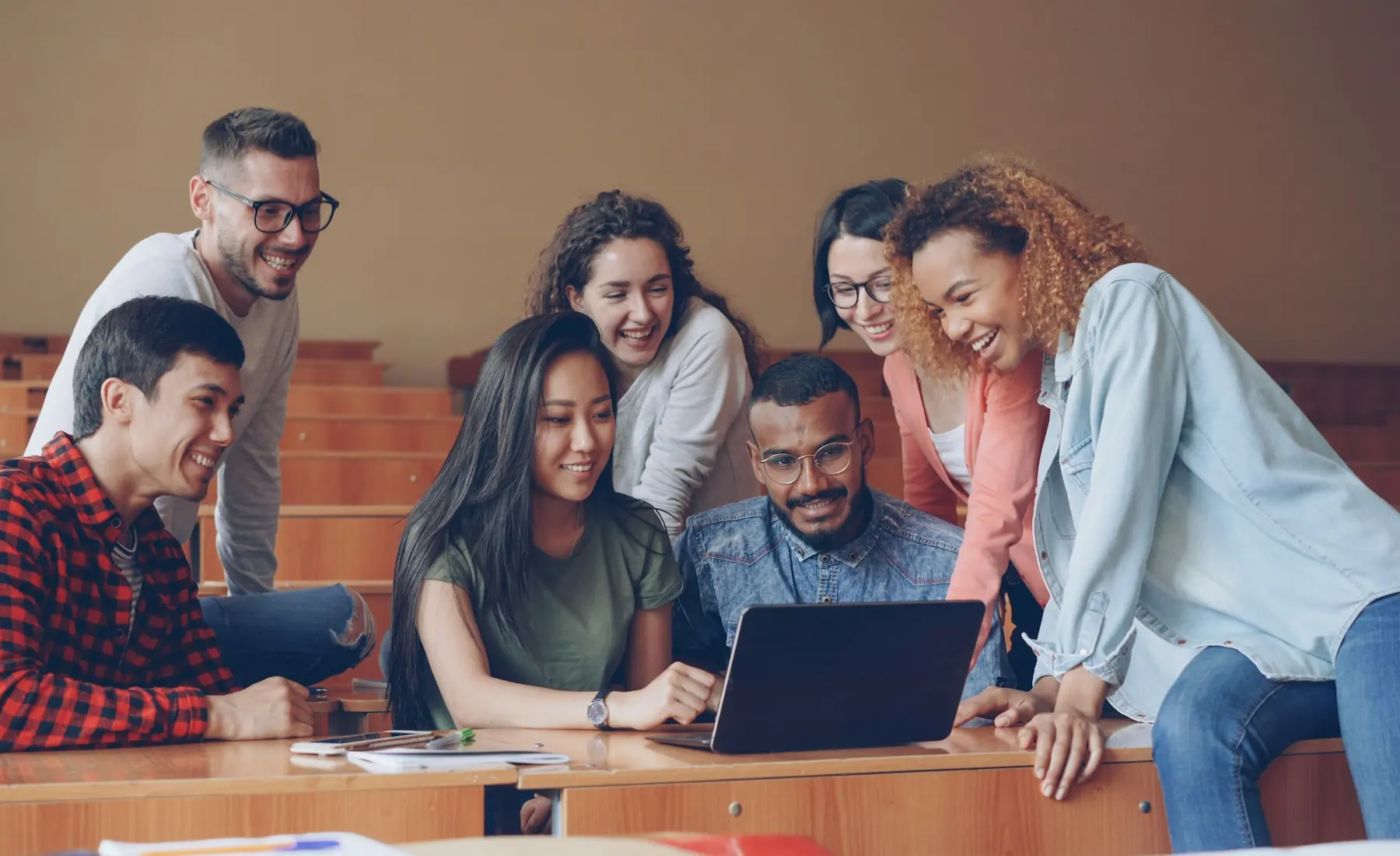 Students gathered around a laptop in a classroom