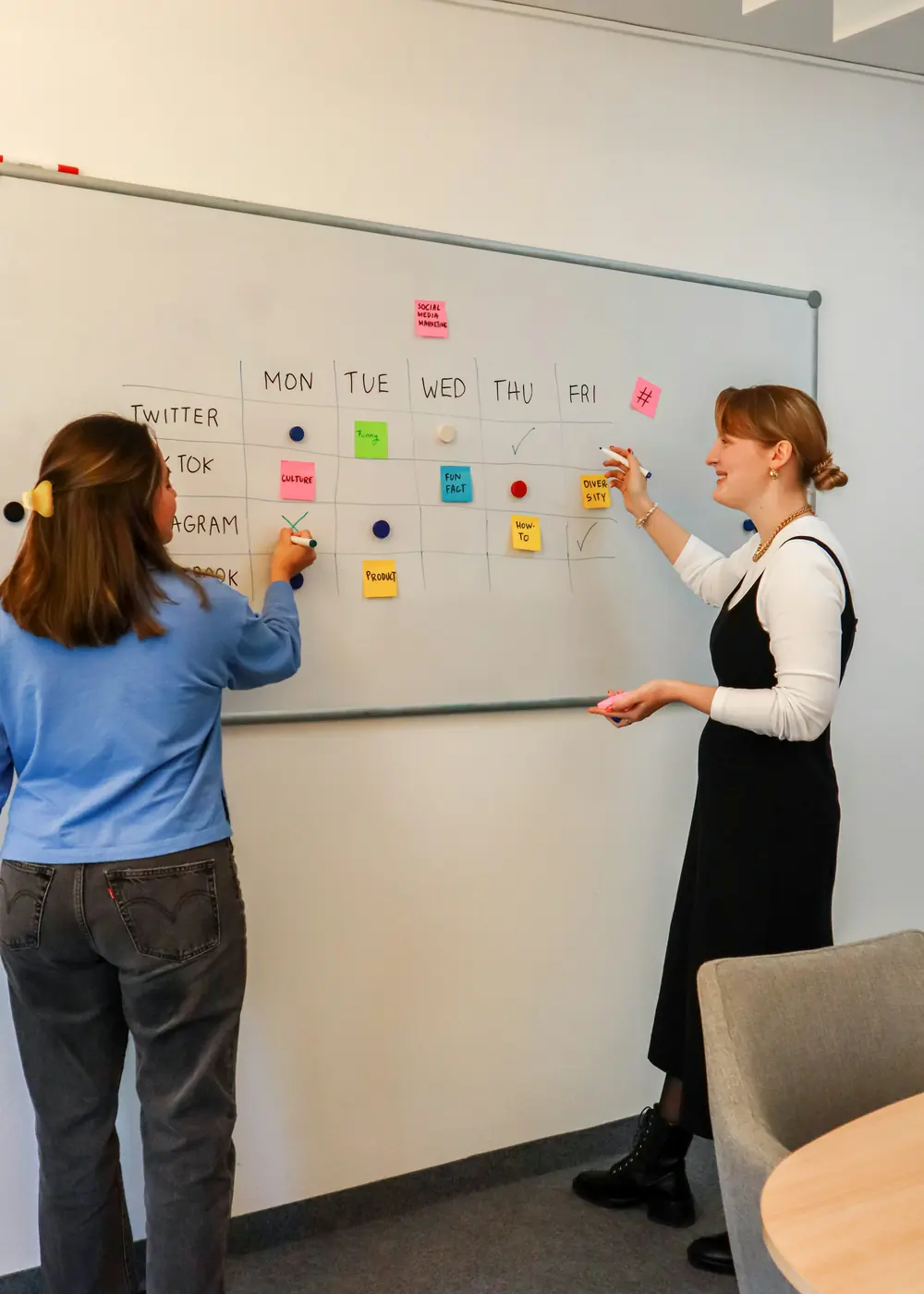Two students planning the week on a whiteboard